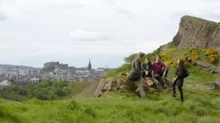 Group of students sitting on arthur's seat (hill) with view of Edinburgh in background