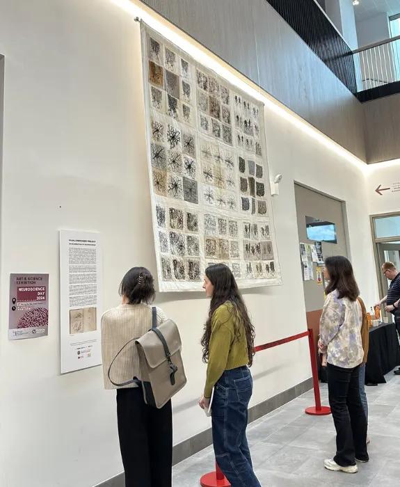 three people looking at an art display on a wall